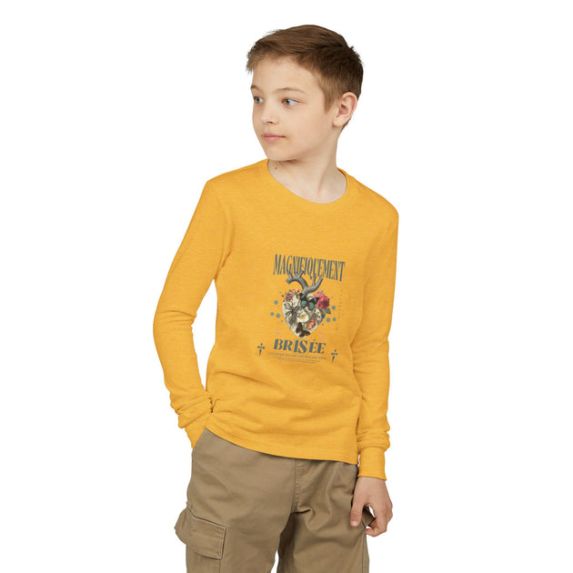 Un enfant porte un t-shirt jaune à manches longues avec un motif de cœur floral et du texte.