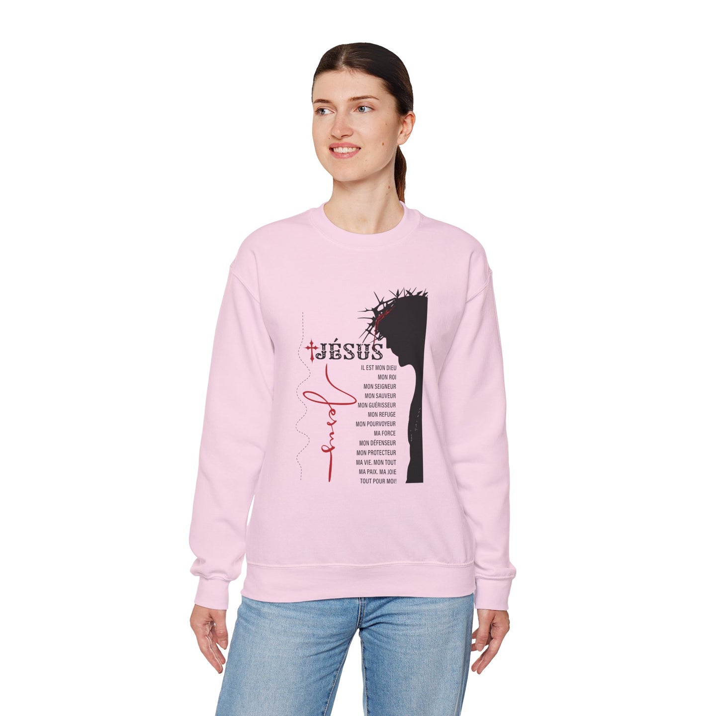 Une femme porte un sweatshirt rose clair orné d'une illustration religieuse et de texte en français.