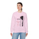 Une femme porte un sweatshirt rose clair orné d'une illustration religieuse et de texte en français.