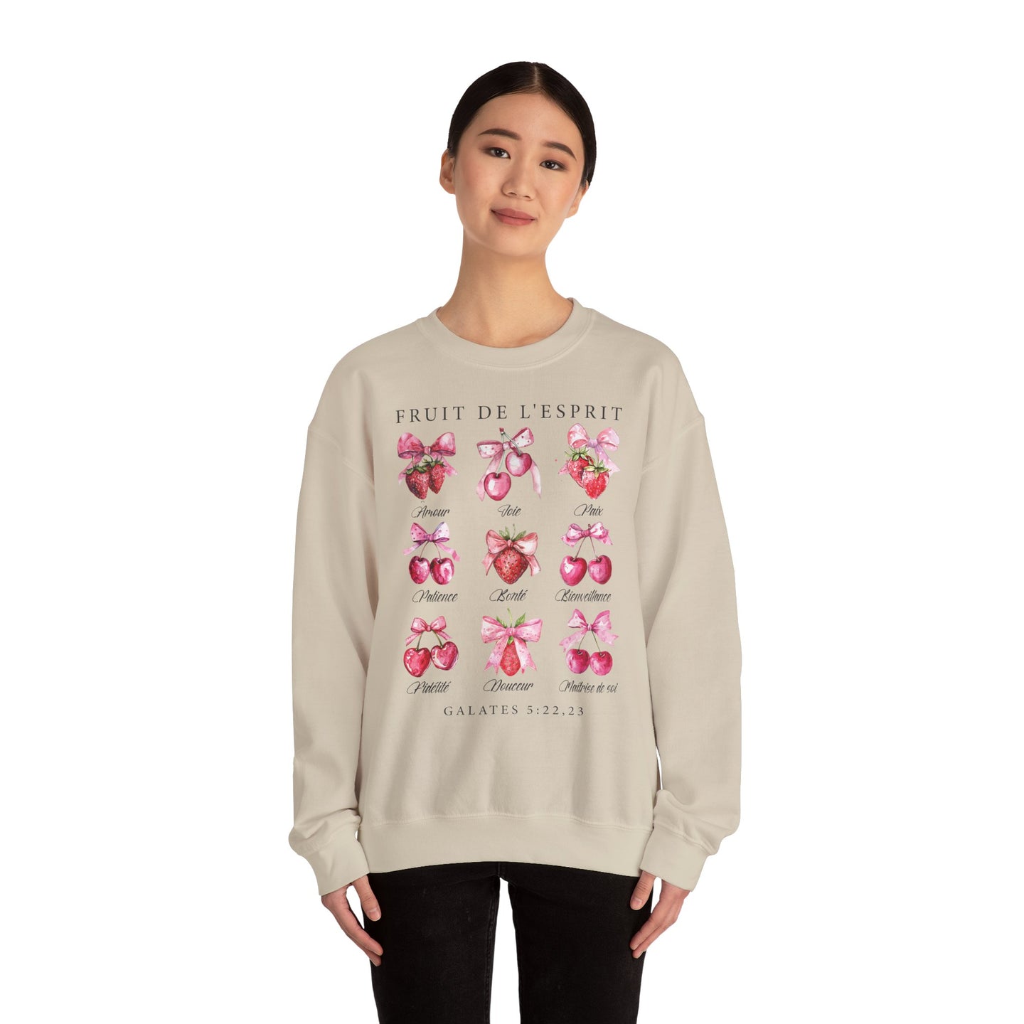Une femme porte un sweat-shirt beige orné d'illustrations de fruits et de textes bibliques.