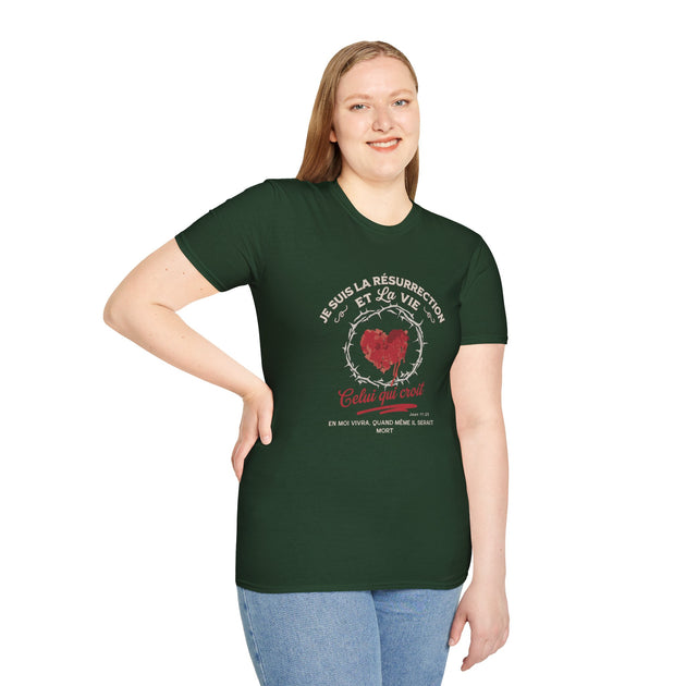Une femme porte un t-shirt vert foncé avec un motif religieux représentant un cœur et une couronne.