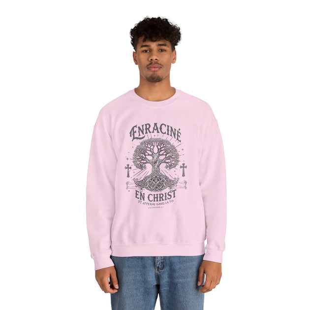 Un homme porte un sweatshirt rose pâle avec une illustration d'arbre et le texte Enraciné en Christ.