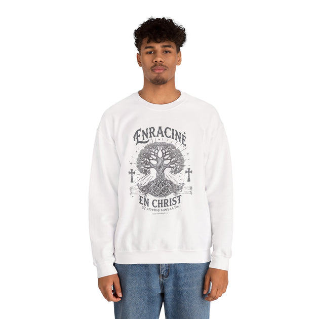 Un homme porte un sweatshirt blanc avec un motif d'arbre et le texte Enraciné en Christ.