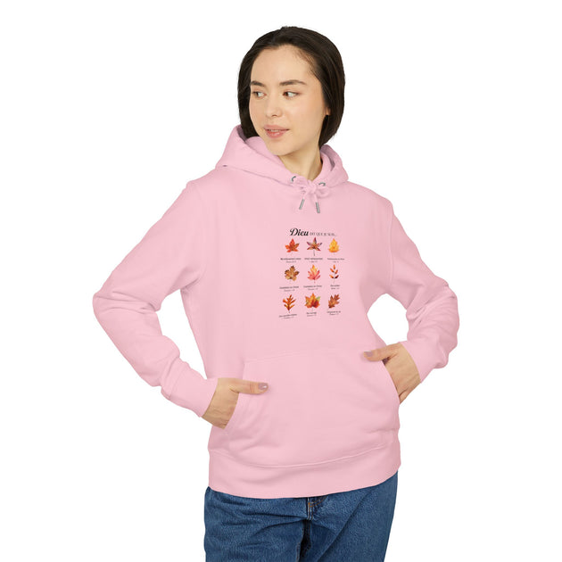 Une femme porte un sweat à capuche rose orné d'un motif de feuilles et de textes bibliques.