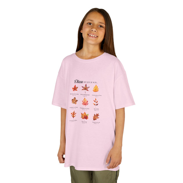 Une jeune fille porte un t-shirt rose clair orné d'un motif de feuilles et de textes religieux.