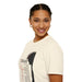 Une femme porte un t-shirt beige en coton orné d'une couronne d'épines et de textes religieux.