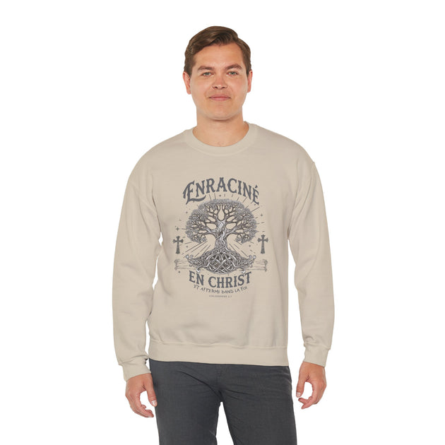 Un homme porte un sweatshirt beige avec une illustration d'arbre et le texte Enraciné en Christ.