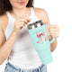 Une femme tient un mug isotherme bleu clair avec un nœud rose et un verset biblique imprimés.