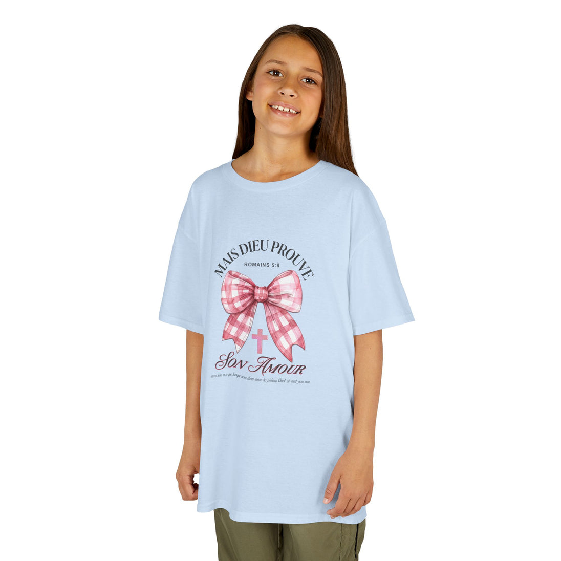 Une jeune fille porte un t-shirt bleu clair avec un motif de nœud rose et une croix chrétienne.