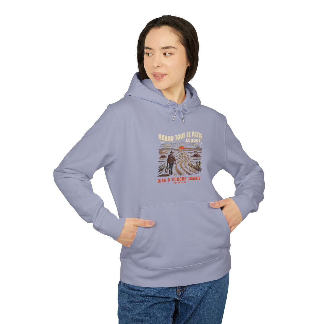 Une femme porte un sweat à capuche bleu clair avec une illustration de voyageur et un texte religieux.