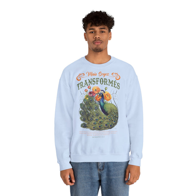 Un homme porte un sweat-shirt bleu clair orné d'un paon, de fleurs et du texte biblique Romains 12:2.