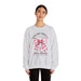 Une femme porte un sweat-shirt gris chiné orné d'un nœud rose à carreaux et d'une croix.