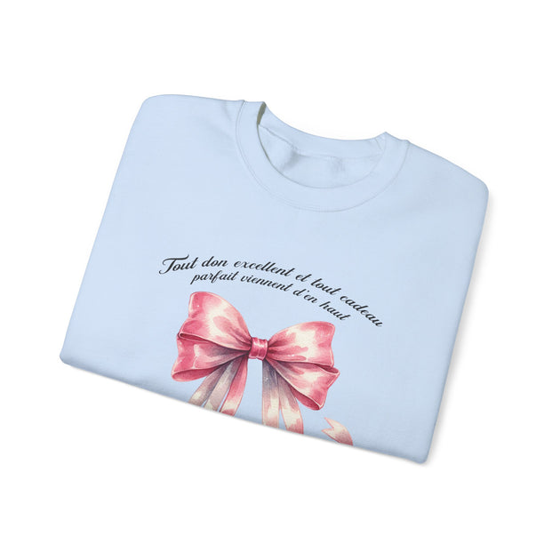 Sweatshirt bleu clair plié avec un ruban rose aquarelle et une inscription en français.