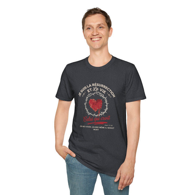 Un homme porte un t-shirt gris foncé avec un motif de cœur entouré d'épines et un texte religieux.