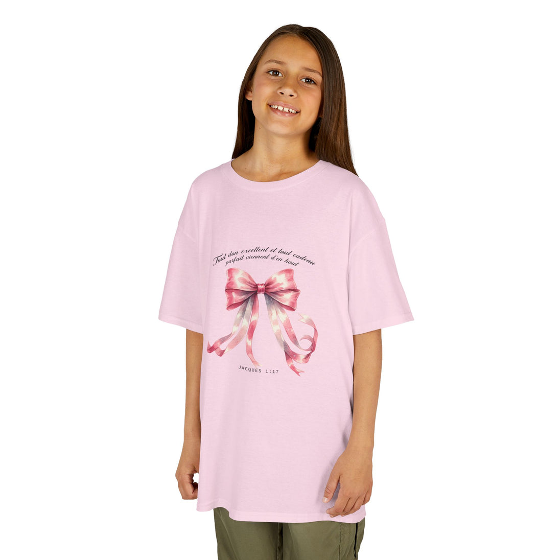 Une enfant porte un t-shirt rose orné d'un ruban aquarelle et du verset Jacques 1:17.
