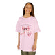 Une enfant porte un t-shirt rose orné d'un ruban aquarelle et du verset Jacques 1:17.