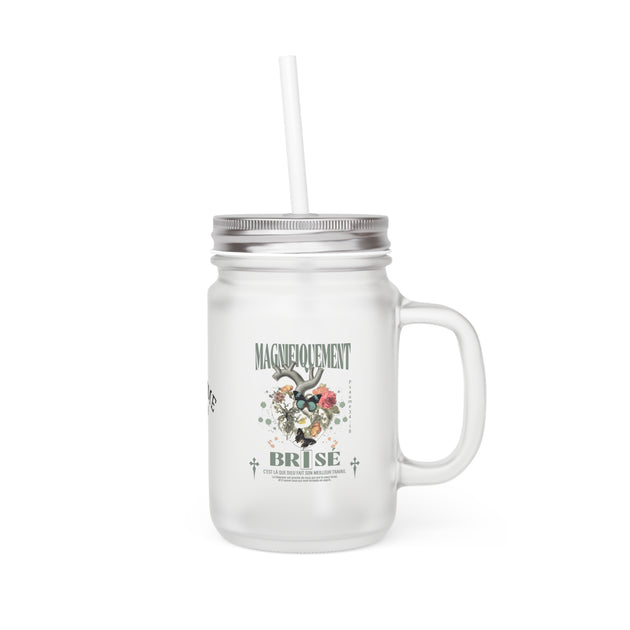 Bocal en verre dépoli avec couvercle métallique, paille et motif floral avec texte.