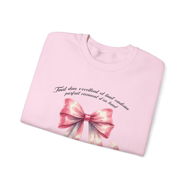 Sweatshirt rose pâle plié avec un ruban aquarelle et une inscription en français sur le torse.