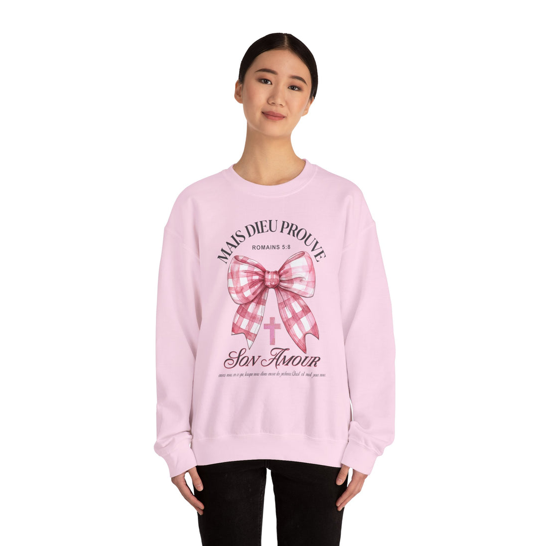 Une femme porte un sweat-shirt rose pâle orné d'un nœud à carreaux et d'un message religieux.