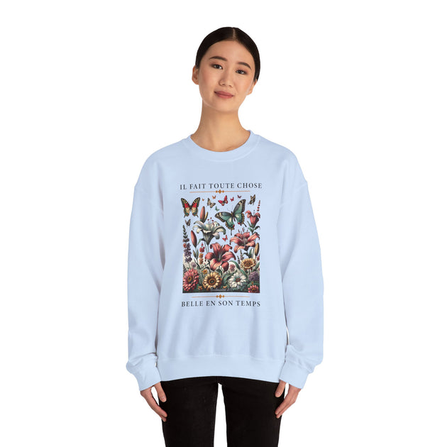 Une femme porte un sweatshirt bleu clair orné d'un motif floral et de papillons avec du texte.