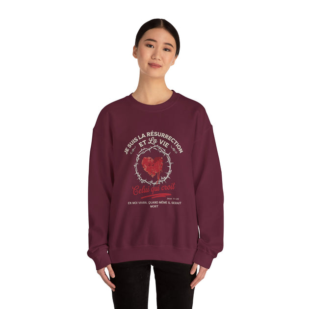 Une femme porte un sweat-shirt bordeaux avec un motif de cœur couronné d'épines et du texte.