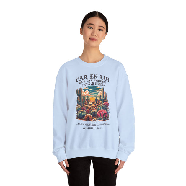 Une femme porte un sweat-shirt blanc illustré d'un paysage désertique et d'un verset biblique.