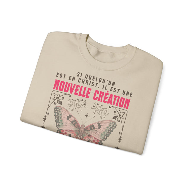 Sweat-shirt beige plié avec un papillon et le texte Si quelqu'un est en Christ, il est une création.