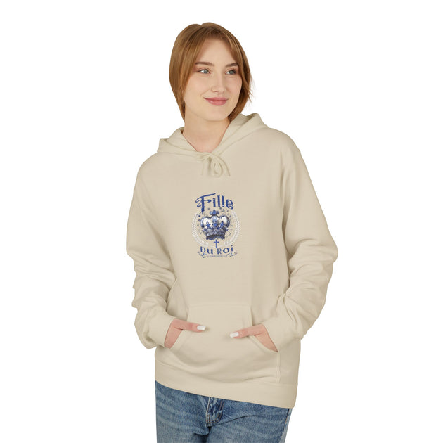 Une femme porte un sweat à capuche beige avec une couronne bleue et le texte Fille du Roi.
