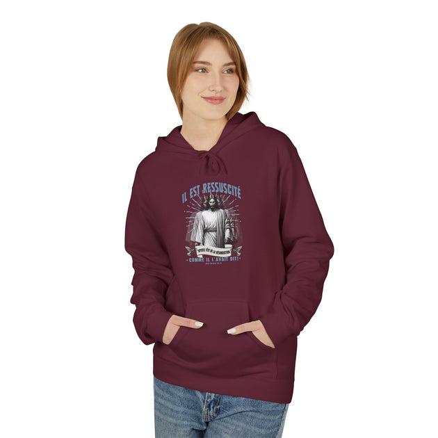 Une femme porte un sweat à capuche bordeaux avec une illustration religieuse sur la poitrine.