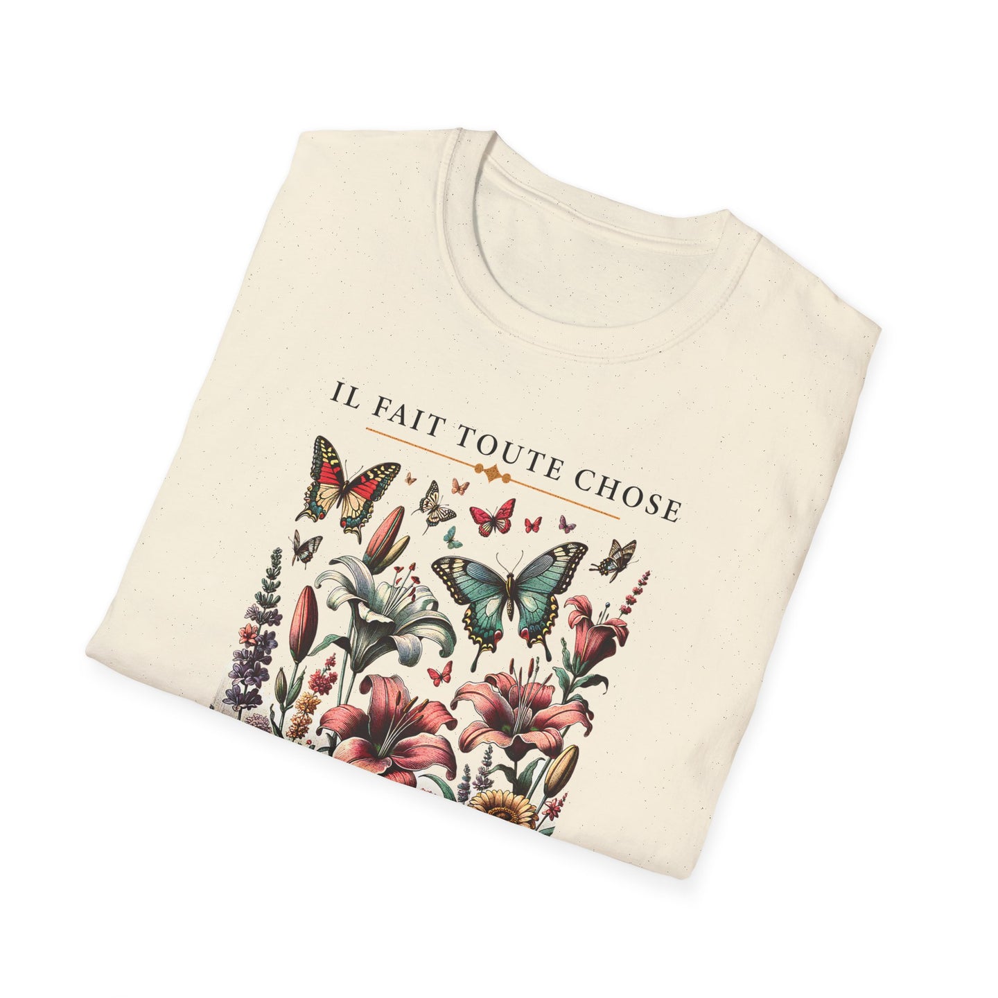 T-shirt beige plié avec une illustration de fleurs et de papillons et le texte Il fait toute chose.