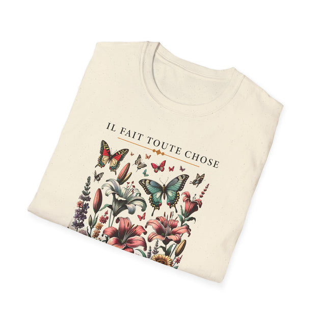 T-shirt beige plié avec une illustration de fleurs et de papillons et le texte Il fait toute chose.