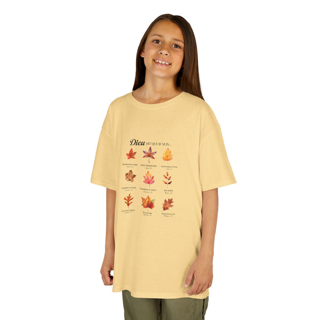 Une jeune fille porte un t-shirt jaune pâle orné d'un motif de feuilles et de textes religieux.