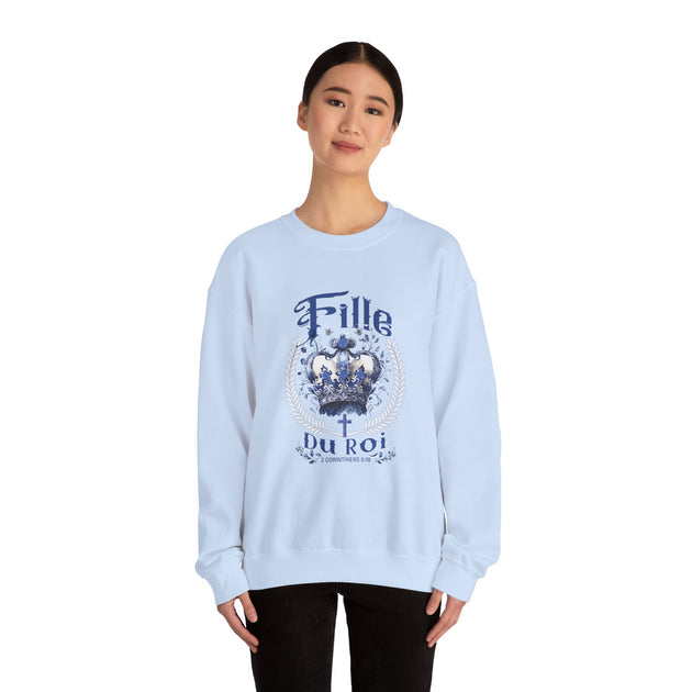 Une femme porte un sweatshirt bleu clair avec une couronne et le texte Fille du Roi.