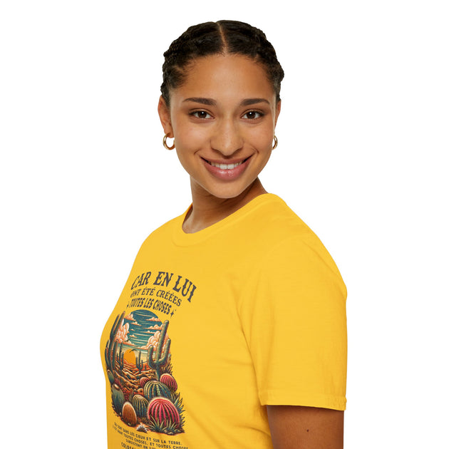 Une femme porte un t-shirt jaune avec une illustration de cactus et un texte religieux en français.