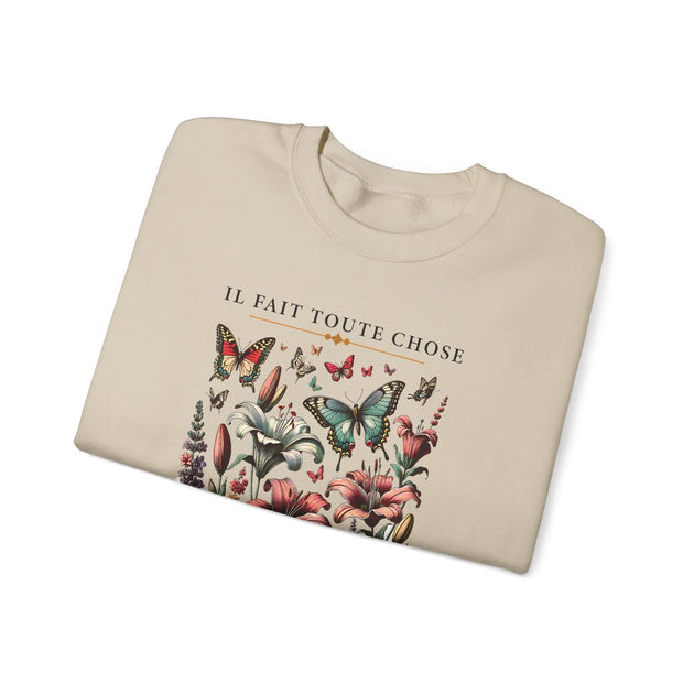 Sweatshirt beige plié orné d'un motif de fleurs et de papillons avec l'inscription Il fait toute chose.