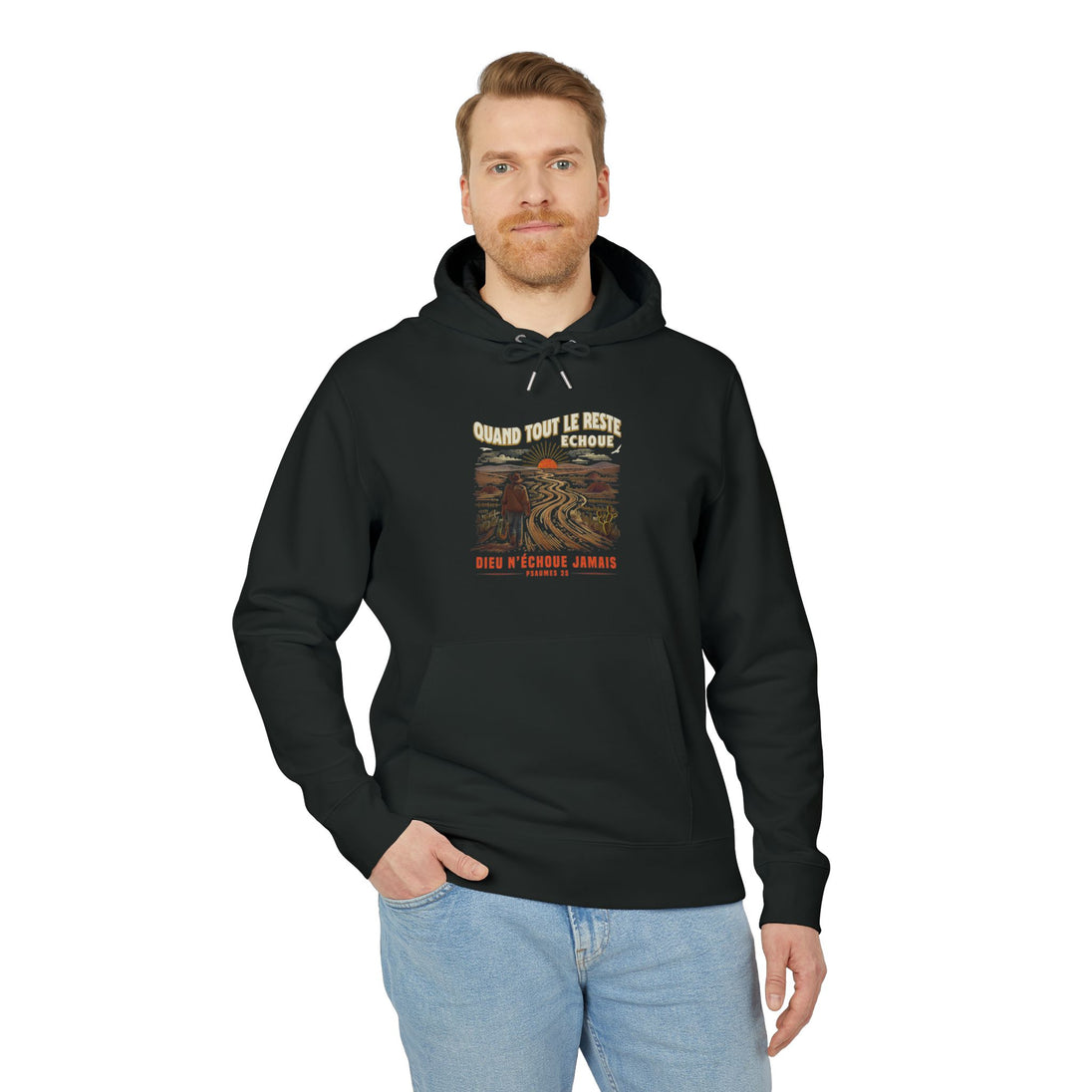 Un homme porte un sweat à capuche noir avec une illustration de paysage et un texte religieux.