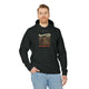 Un homme porte un sweat à capuche noir avec une illustration de paysage et un texte religieux.