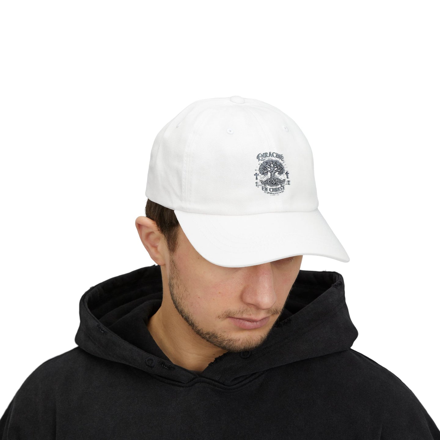 Un homme porte une casquette blanche en coton avec le motif Enracine en Christ brodé sur le devant.