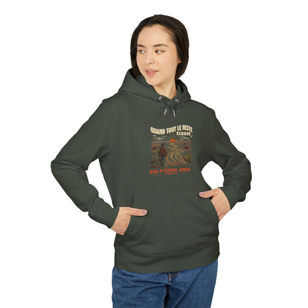 Une femme porte un sweat à capuche vert foncé avec une illustration de paysage et du texte.