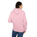 Une femme porte un sweat à capuche rose uni vu de dos sur un fond blanc.