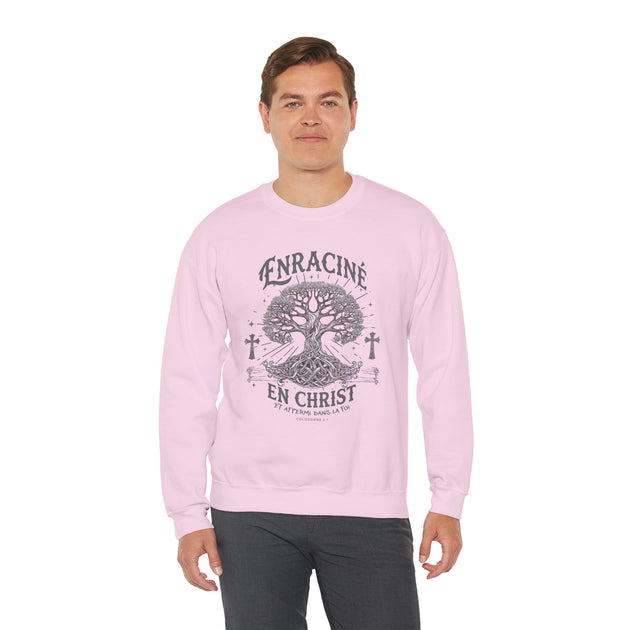 Un homme porte un sweatshirt rose clair avec une illustration d'arbre et le texte Enraciné en Christ.