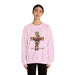 Une femme porte un sweat-shirt rose pâle orné d'une croix florale et de l'inscription Tout est accompli.
