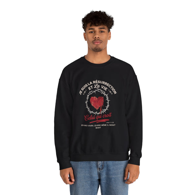 Un homme porte un sweatshirt noir avec un motif religieux représentant un cœur entouré d'épines.