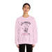 Une femme porte un sweat-shirt rose pâle avec une empreinte de main et un texte religieux.