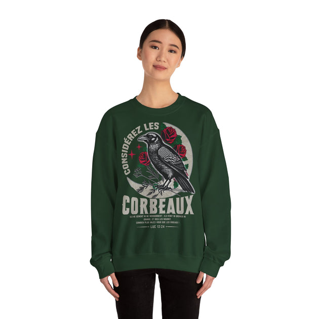 Une femme porte un sweatshirt vert foncé illustré d'un corbeau, de roses et d'un verset biblique.