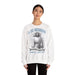 Une femme porte un sweatshirt blanc avec une illustration religieuse et le texte Il est ressuscité.
