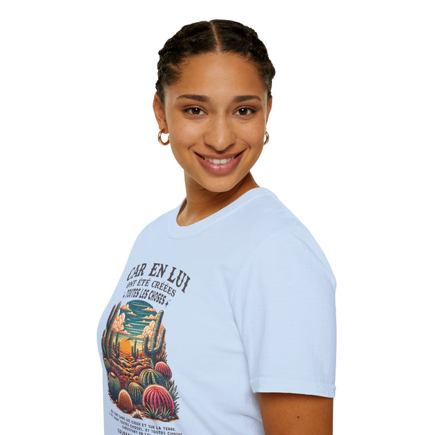 Une femme porte un t-shirt bleu clair avec une illustration de cactus et un texte religieux.