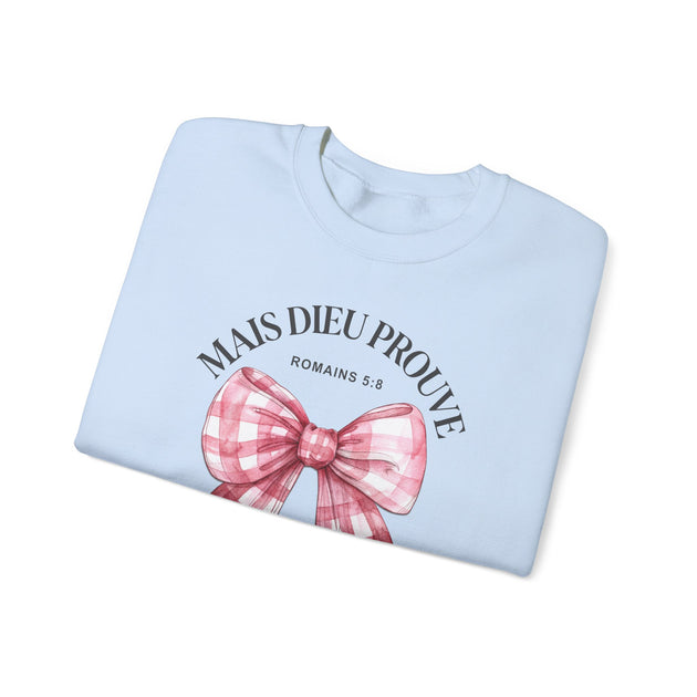 Sweat-shirt bleu clair plié avec un nœud rose à carreaux et l'inscription Mais Dieu Prouve.
