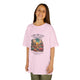 Une jeune fille porte un t-shirt rose en coton avec une illustration de désert et un texte biblique.