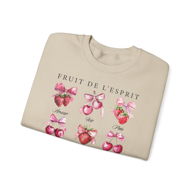 Sweat-shirt beige plié orné d'illustrations de fraises et de cerises avec des nœuds roses.